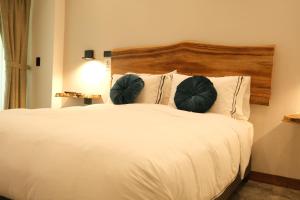 sypialnia z białym łóżkiem z 2 zielonymi poduszkami w obiekcie UKO Urban Ekolodge w mieście Armenia