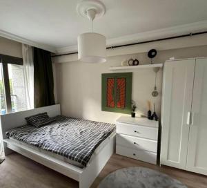 - une chambre blanche avec un lit et une commode dans l'établissement Nalyapan Apartmanı, à Konak