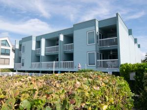 een blauw appartementencomplex met struiken ervoor bij Seaside Beach House 203 in Holmes Beach
