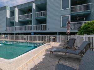 een patio met 2 stoelen en een zwembad bij Seaside Beach House 203 in Holmes Beach
