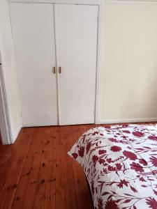 1 dormitorio con armarios blancos, 1 cama y suelo de madera en Oakdale guest house en Ciudad del Cabo