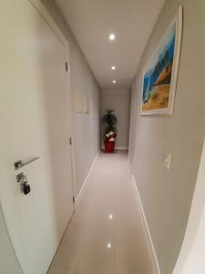 Un pasillo blanco con una planta en una olla en Apartamento praia Bombas com 2 quartos cobertura, en Bombinhas