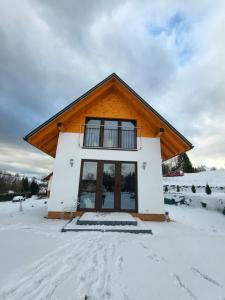 a house with snow on the ground in front of it at Domek Bieszczadzki Staw - Noclegi Czarna in Czarna