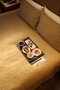 a tray with two plates of food on a bed at San Want Residences Taipei in Taipei