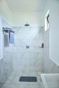a white bathroom with a shower and a sink at Monarch Villas - Kilifi in Vipingo