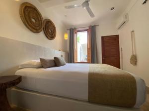 a bedroom with a large white bed and a window at Casa Nuup Holbox in Holbox Island