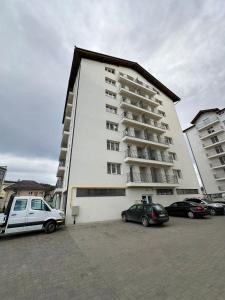 Un gran edificio blanco con coches aparcados en un estacionamiento. en Apartament Rose, en Gura Humorului