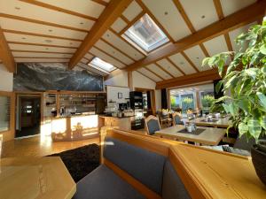 una sala de estar con techos de madera y mesas y sillas de madera. en Hotel AlpIn Bed & Breakfast, en Fischen