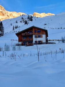 a building in a snow covered field with mountains at Sunny Arabba Apartment in Arabba