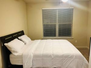 Schlafzimmer mit einem Bett mit weißer Bettwäsche und einem Fenster in der Unterkunft Home at Energy corridor in Houston