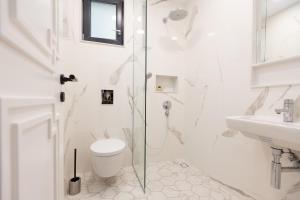 a white bathroom with a toilet and a sink at Luxury rooms 12-1 in Plovdiv