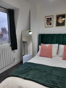 a bedroom with a bed with a green headboard and a mirror at 20 mins to central London, Stylish sky views 2 bed in London