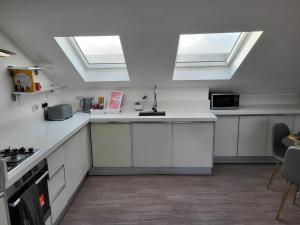 eine Küche mit weißen Schränken und Oberlichtern an der Decke in der Unterkunft 20 mins to central London, Stylish sky views 2 bed in London
