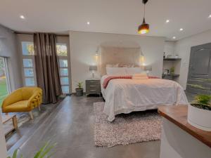 1 dormitorio con 1 cama grande y 1 silla amarilla en Amoris Guesthouse - Sandton, en Johannesburgo