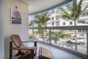 Cette chambre dispose d'une chaise et d'une grande fenêtre. dans l'établissement Lindo apto a 3 minutos da praia de Jurerê VMA101, à Florianópolis
