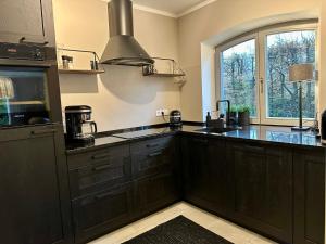 a kitchen with black cabinets and a large window at Dünenhof DÜNENHOF Whg. D-01 in Wustrow
