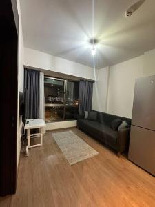 ein Wohnzimmer mit einem schwarzen Sofa und einem Kühlschrank in der Unterkunft Merkezi, havuzlu, lüx site içerisinde komförlü homeoffice in Istanbul