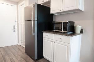 a kitchen with a black refrigerator and white cabinets at Oceanfront Escape with Private Porch 1st Floor in Pawleys Island