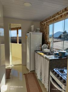 a kitchen with a white refrigerator and a sink at Suítes Carla e Carol in Praia de Araçatiba