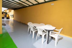 una mesa y sillas blancas contra una pared amarilla en The Safe Point Residential Castillo, en Castillo del Romeral