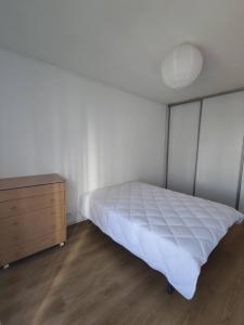a bedroom with a white bed and a dresser at Grand Logement à 15 min de la mer in Perpignan