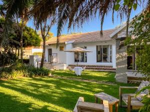 una casa bianca con cortile, tavolo e panche di Amoris Guesthouse - Sandton a Johannesburg
