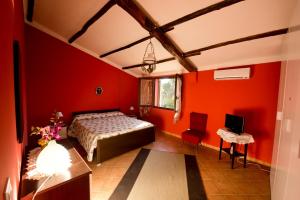 a bedroom with red walls and a bed and a desk at La Mimosa Case Vacanze in Marsala