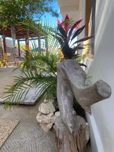 een standbeeld van een persoon die op een stronk naast een plant zit bij Casa Nuup Holbox in Holbox Island