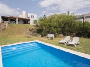 a blue swimming pool with two chairs and a house at Casa hermosa vista in Villa Carlos Paz