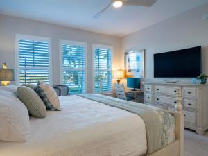 Schlafzimmer mit einem Bett, einem TV und Fenstern in der Unterkunft Otter Lagoon at One Particular Harbour 379-103 in Bradenton
