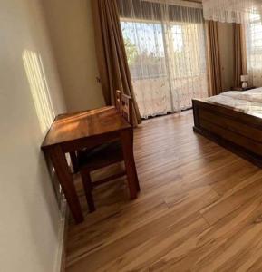 um quarto com uma mesa de madeira ao lado de uma cama em Nalya Apartments em Kampala