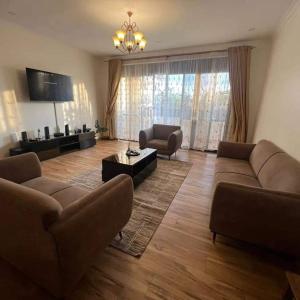 uma grande sala de estar com sofás e uma televisão em Nalya Apartments em Kampala