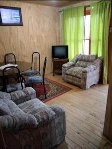 Sala de estar con 2 sofás y TV en cabañas de la casona, en Punta de Choros