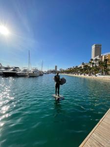 un hombre está de pie en una tabla de surf en el agua en Habitación Sol Connect, en Alicante