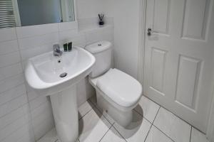 a white bathroom with a toilet and a sink at Modern Comfort 2BR Apartment - FREE Parking - FAST Internet in Oadby