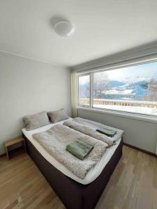 1 dormitorio con 1 cama grande y ventana grande en Leilighet med egen uteplass og utsikt. Parkering., en Svolvær