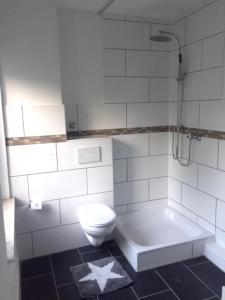 uma casa de banho com um WC, um chuveiro e uma banheira em Große möblierte Wohnung im Zentrum von Lage em Lage