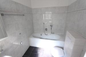 uma casa de banho branca com uma banheira e um WC em Große möblierte Wohnung im Zentrum von Lage em Lage