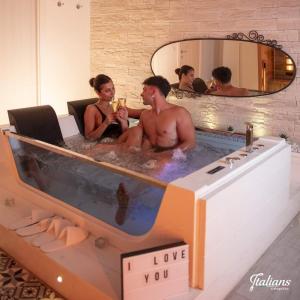Un uomo e una donna seduti in una vasca da bagno di Italians b&b luxury suite ad Acquaviva delle Fonti
