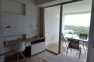 1 dormitorio con ventana grande y mesa con ordenador portátil en New Beach loft in Cartagena close to the airport, en Cartagena de Indias