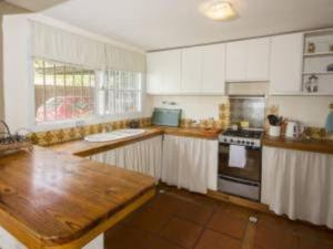 cocina con armarios blancos y encimera de madera en Casa hermosa vista en Villa Carlos Paz