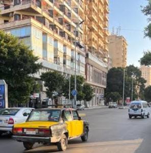 a yellow car is driving down a city street at برج سما الحرية in Alexandria