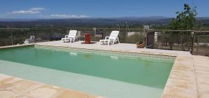 a swimming pool with two chairs and a table at Estancia de Campo in Estancia Vieja
