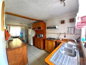 una cocina con armarios de madera y fregadero en Casa de descanso Olmue, en Olmué