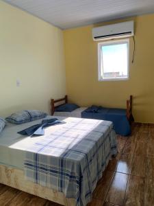 een slaapkamer met 2 bedden en een raam met airconditioning bij Pousada São Benedito in Cachoeira Paulista