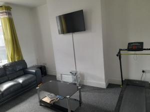 sala de estar con sofá y TV en la pared en ACCANE, en Monkwearmouth