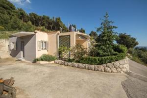 a house with a fence and a tree in the driveway at Apartment Ela with private jacuzzi in Podgora