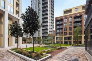 a courtyard with benches and trees and buildings at Brand New 1 Bed Modern Apartment in London