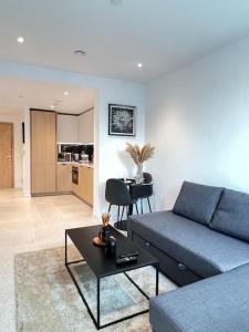 a living room with a blue couch and a table at Brand New 1 Bed Modern Apartment in London