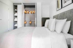 a bedroom with a large white bed with white pillows at Brand New 1 Bed Modern Apartment in London